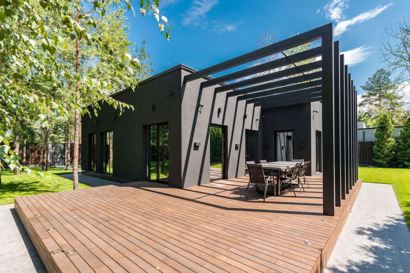 Casa modular contemporânea com amplo deck de madeira e pérgola, num dia de sol