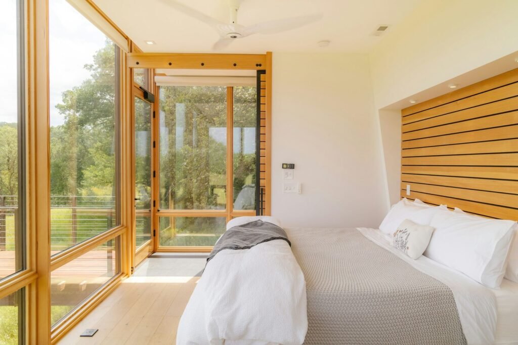 Quarto espaçoso com parede envidraçada para a natureza e cabeceira em ripado de madeira