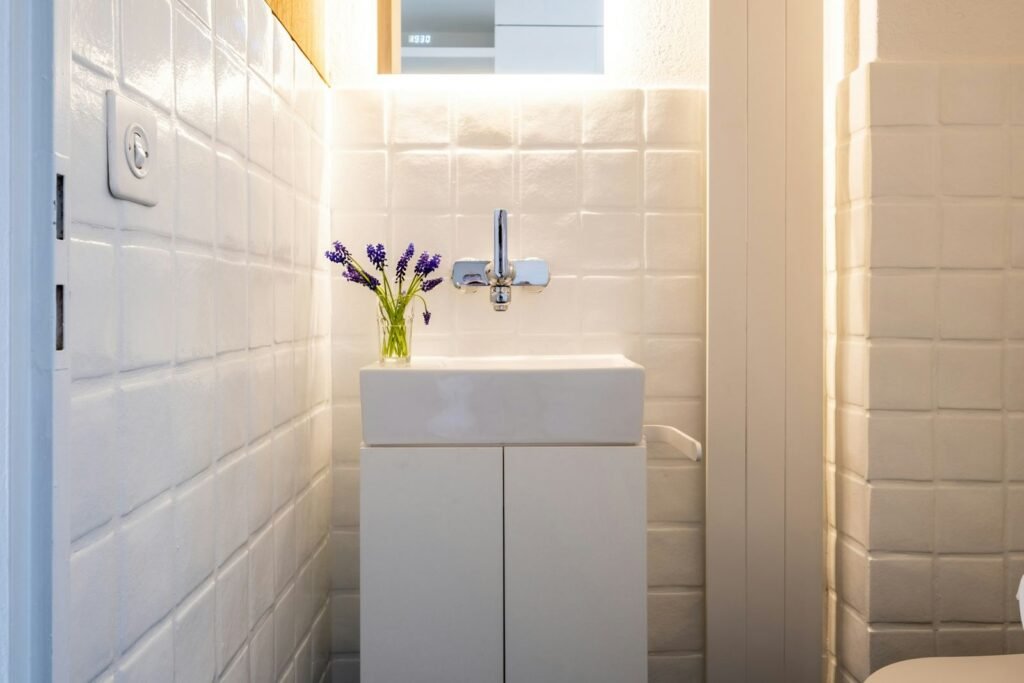 Casa de banho compacta com azulejo branco em relevo e lavatório suspenso