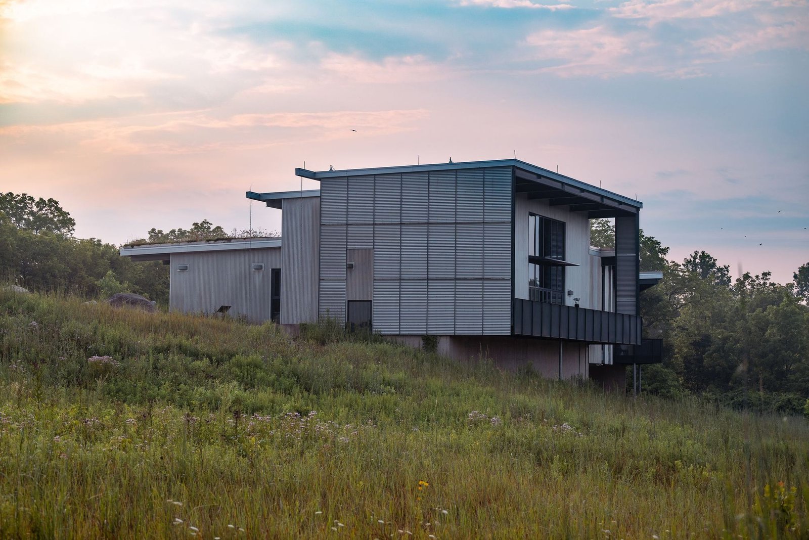 Casa modular contemporânea numa encosta relvada ao pôr do sol