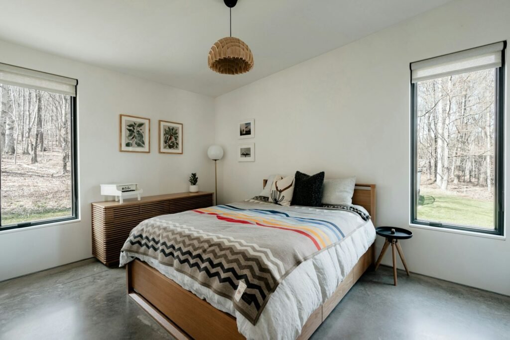 Quarto luminoso com cama de madeira e janelas para o jardim