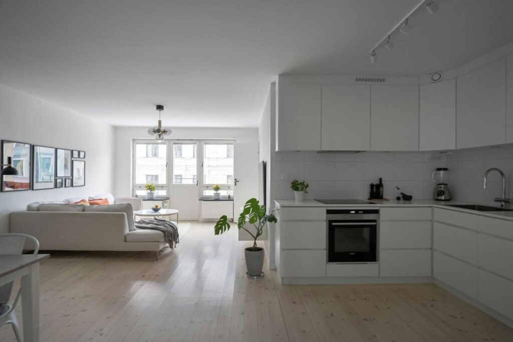 Sala e cozinha em open space, com móveis brancos e pavimento claro