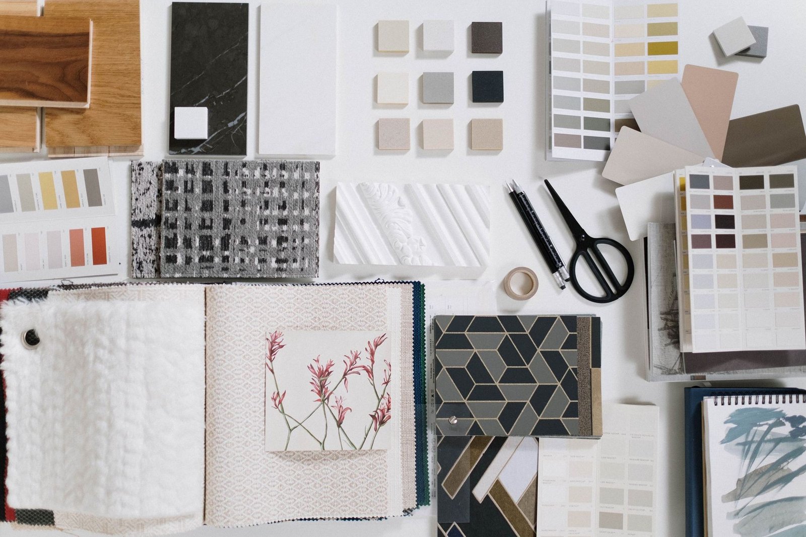 Amostras de materiais sobre a mesa: madeira, pedra, azulejos, tecidos e cartas de cores