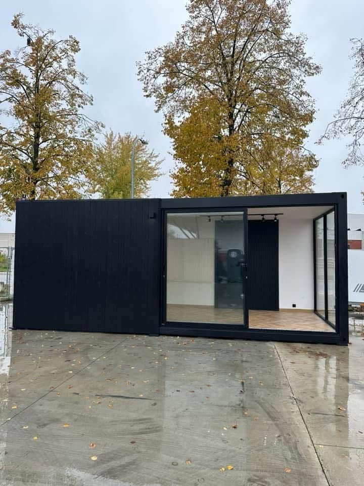 Fachada do edifício modular preto com grandes vãos envidraçados e interior iluminado