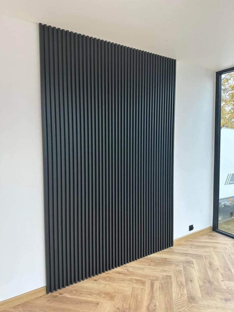 Parede interior com painel decorativo em ripado preto e pavimento em espinha